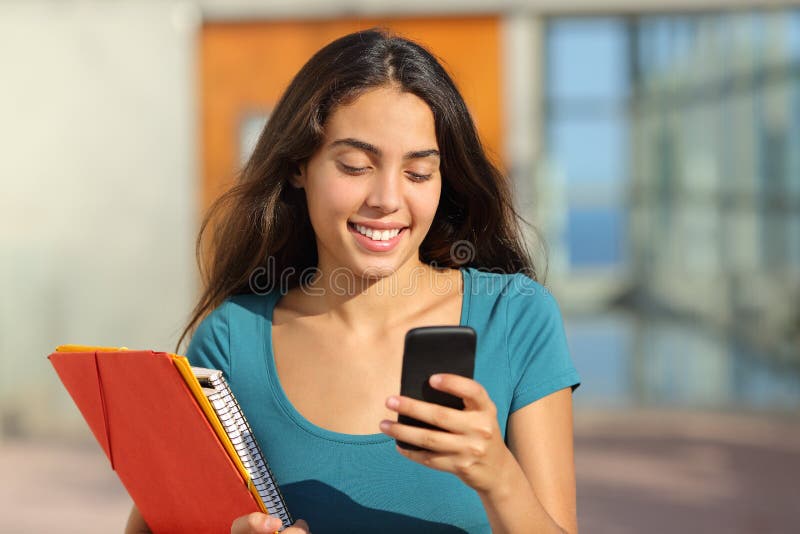 Fille d'adolescent d'étudiant marchant tout en regardant son téléphone intelligent photos libres de droits