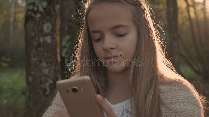 Fille d'adolescent revoir le téléphone intelligent dans le parc banque de vidéos
