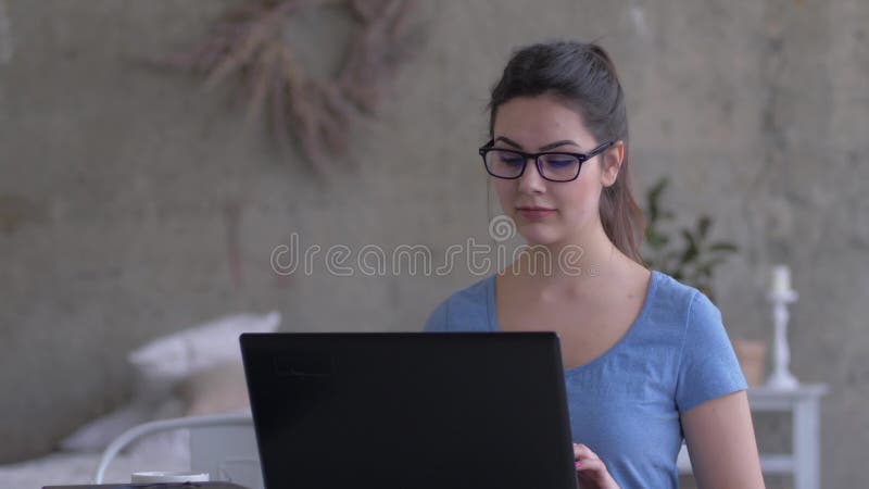 Fille d'affaires avec le fonctionnement en verre à la maison se reposant au texte de dactylographie d'ordinateur portable et reg