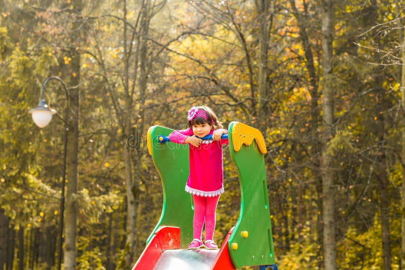 Fille d'enfant en bas âge ayant l'amusement au terrain de jeu par jour d'automne photos libres de droits Fille d'enfant en bas âge ayant l'amusement au terrain de jeu par jour d'automne photos libres de droits