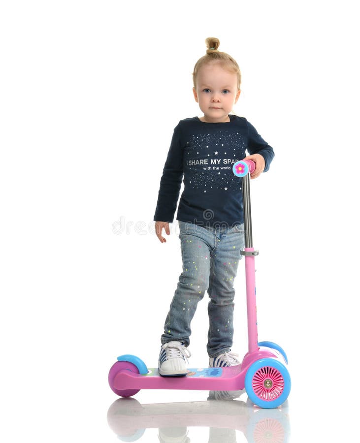 Fille d'enfant en bas âge de petit enfant apprenant à monter et équilibrer sur la poussée t image stock Fille d'enfant en bas âge de petit enfant apprenant à monter et équilibrer sur la poussée t image stock