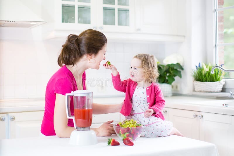 Fille d'enfant en bas âge et mère adorable faisant la fraise fraîche photos stock Fille d'enfant en bas âge et mère adorable faisant la fraise fraîche photos stock
