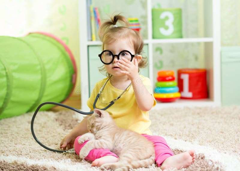 Fille d'enfant jouant docteur With A Cat In Nursery photos stock Fille d'enfant jouant docteur With A Cat In Nursery photos stock