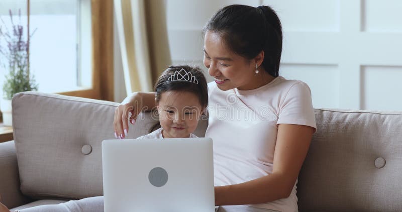 Fille d'enseignement des enfants de mère asiatique à l'aide de l'ordinateur portable pour l'éducation d'enfants