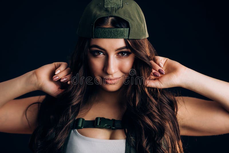 Fille dans le chapeau militaire souriant et regardant la caméra sur un fond noir photos libres de droits Fille dans le chapeau militaire souriant et regardant la caméra sur un fond noir photos libres de droits