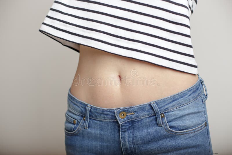 Girl in blue jeans and a striped sweater and lifted her arms bared belly with a beautiful waist and umbilicus. Girl in blue jeans and a striped sweater and lifted her arms bared belly with a beautiful waist and umbilicus