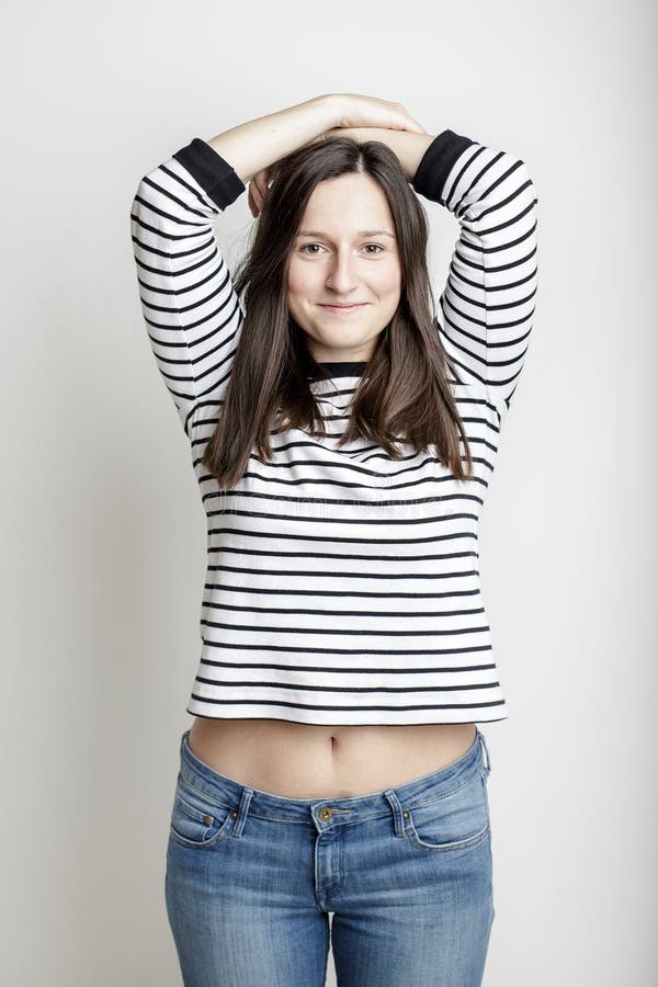 Girl in blue jeans and a striped sweater and lifted her arms bared belly with a beautiful waist and umbilicus. Girl in blue jeans and a striped sweater and lifted her arms bared belly with a beautiful waist and umbilicus