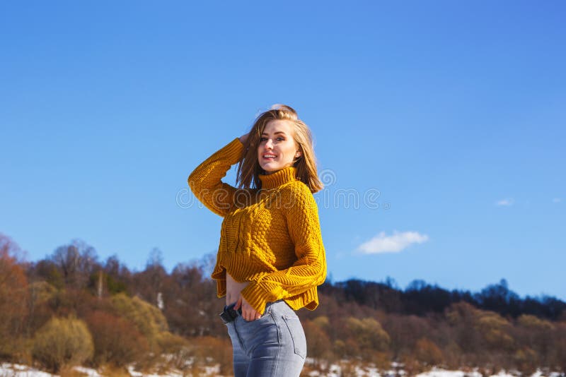 Fille dans un chandail jaune posant contre la forêt de ciel bleu et d'hiver photos libres de droits Fille dans un chandail jaune posant contre la forêt de ciel bleu et d'hiver photos libres de droits