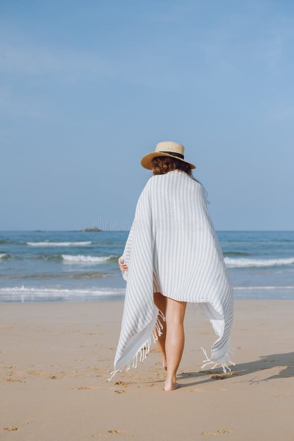 Fille dans un chapeau marchant le long de la plage image stock