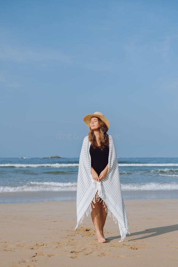 Fille dans un chapeau marchant le long de la plage photos stock