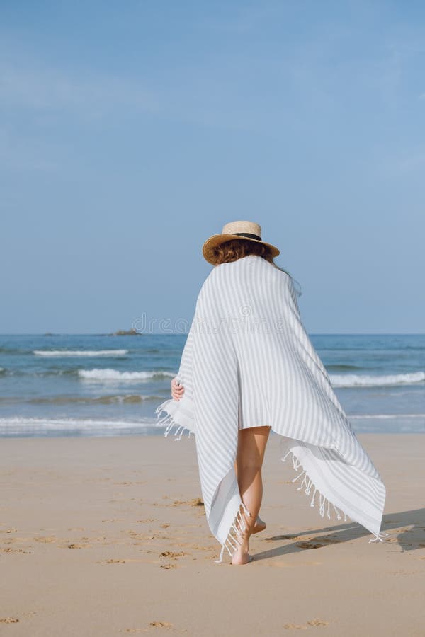 Fille dans un chapeau marchant le long de la plage photographie stock