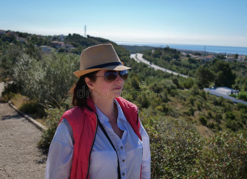 Fille de brune dans un chapeau et regards de lunettes de soleil à la route loin photographie stock libre de droits Fille de brune dans un chapeau et regards de lunettes de soleil à la route loin photographie stock libre de droits