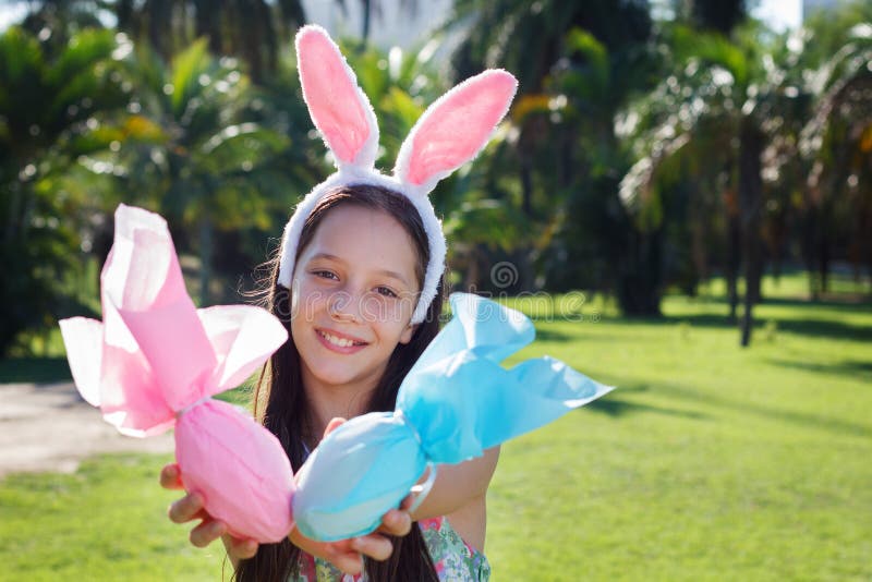 Fille de l'adolescence mignonne de sourire avec des oreilles de lapin tenant le chocolat de Pâques image libre de droits Fille de l'adolescence mignonne de sourire avec des oreilles de lapin tenant le chocolat de Pâques image libre de droits