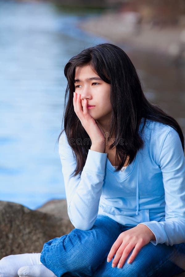 Fille de l'adolescence triste s'asseyant sur des roches le long de rivage de lac, expression isolée photos libres de droits Fille de l'adolescence triste s'asseyant sur des roches le long de rivage de lac, expression isolée photos libres de droits