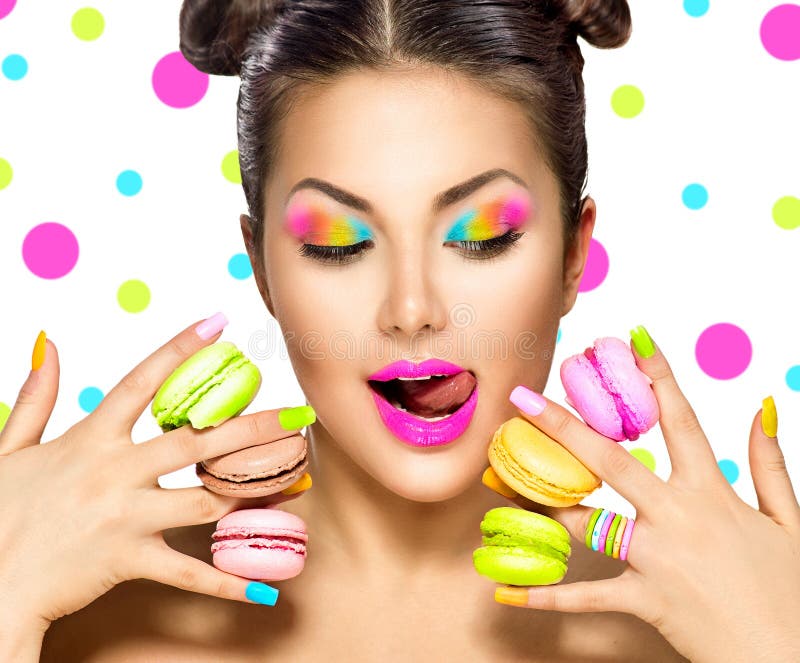 Fille de mannequin de beauté prenant les macarons colorés photos stock Fille de mannequin de beauté prenant les macarons colorés photos stock