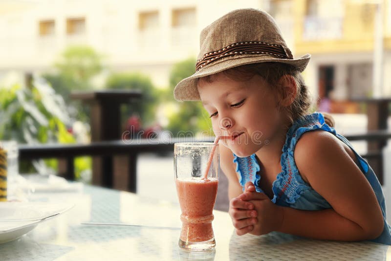 Fille de pensée mignonne d'enfant buvant du jus savoureux photo libre de droits Fille de pensée mignonne d'enfant buvant du jus savoureux photo libre de droits