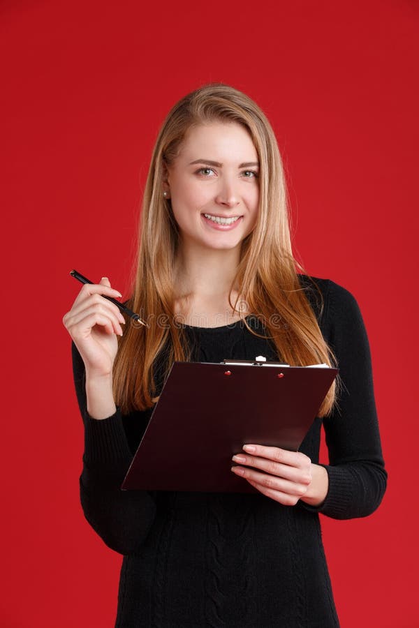Fille de sourire, tenant un presse-papiers avec des papiers et un stylo bille image stock Fille de sourire, tenant un presse-papiers avec des papiers et un stylo bille image stock