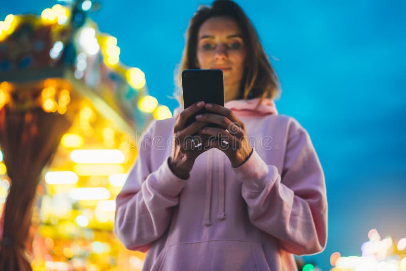 Fille de vue de face dirigeant le doigt sur le smartphone d'écran sur la lumière de bokeh de fond de defocus dans l'attraction de images stock Fille de vue de face dirigeant le doigt sur le smartphone d'écran sur la lumière de bokeh de fond de defocus dans l'attraction de images stock