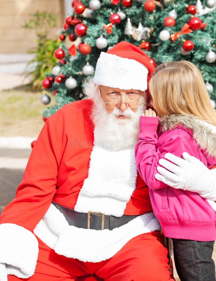 Fille disant le souhait dans l'oreille du père noël photos libres de droits Fille disant le souhait dans l'oreille du père noël photos libres de droits