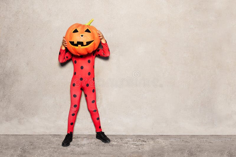 Fille en costume de coccinelle avec tête de grosse citrouille photographie stock libre de droits Fille en costume de coccinelle avec tête de grosse citrouille photographie stock libre de droits