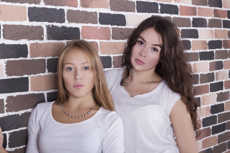 Fille et brune blondes dans des chemises blanches se tenant avec les visages sérieux images stock Fille et brune blondes dans des chemises blanches se tenant avec les visages sérieux images stock