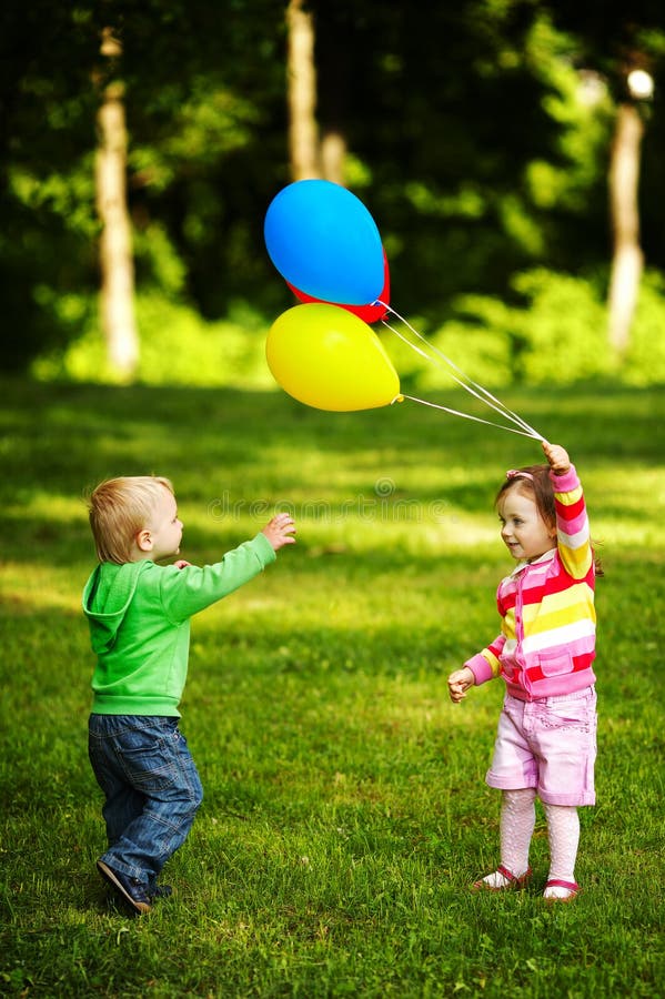Fille et garçon jouant avec des ballons en stationnement image libre de droits Fille et garçon jouant avec des ballons en stationnement image libre de droits