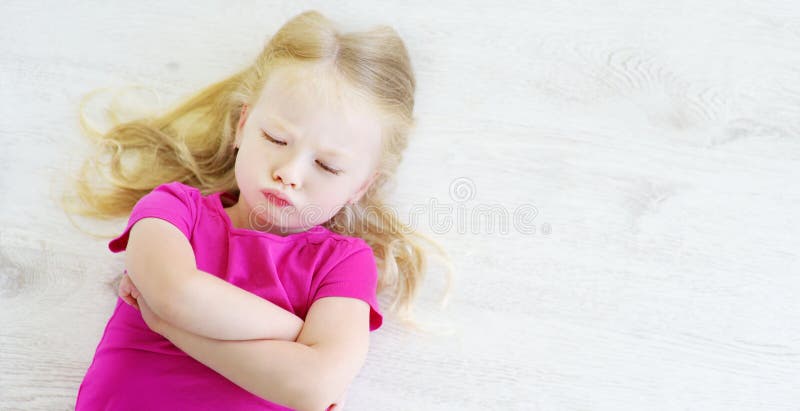 Fille fâchée se trouvant sur le plancher en bois blanc images libres de droits Fille fâchée se trouvant sur le plancher en bois blanc images libres de droits