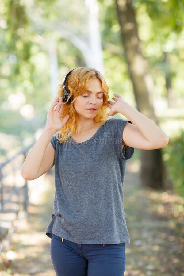 Fille heureuse appréciant la musique Belle femme dans des écouteurs sur un fond de parc Concept actif de style de vie photos libres de droits Fille heureuse appréciant la musique Belle femme dans des écouteurs sur un fond de parc Concept actif de style de vie photos libres de droits