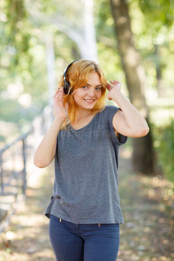 Fille heureuse appréciant la musique Belle femme dans des écouteurs sur un fond de parc Concept actif de style de vie photo libre de droits Fille heureuse appréciant la musique Belle femme dans des écouteurs sur un fond de parc Concept actif de style de vie photo libre de droits