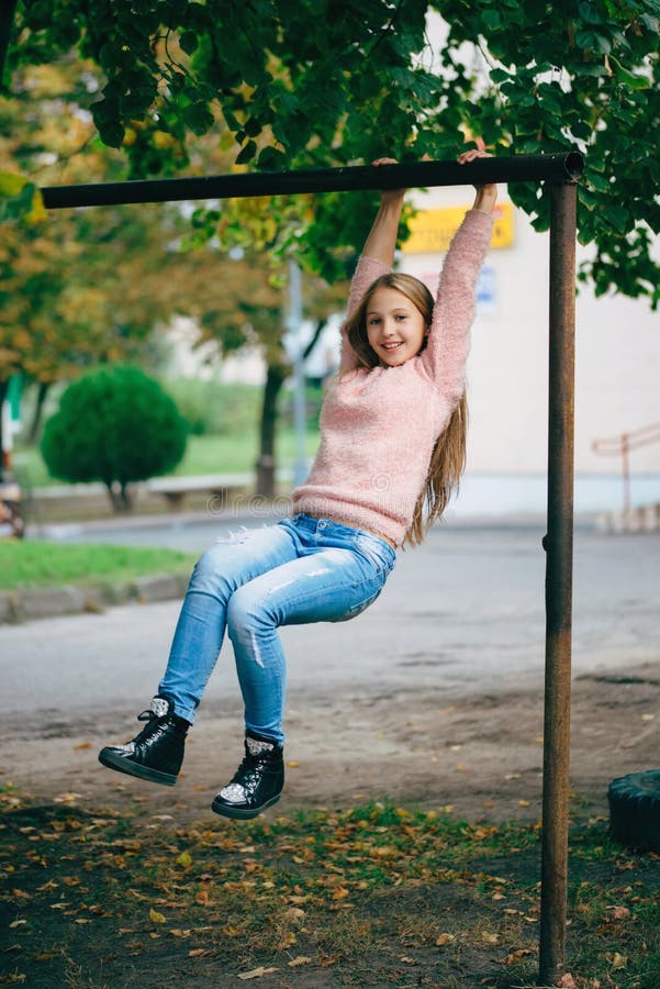Fille heureuse balançant sur la barre transversale photo stock Fille heureuse balançant sur la barre transversale photo stock