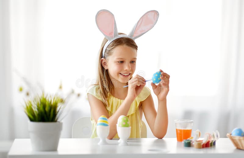 Fille heureuse colorant des oeufs de pâques à la maison photos libres de droits Fille heureuse colorant des oeufs de pâques à la maison photos libres de droits