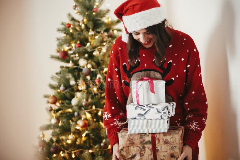 Fille heureuse dans le chapeau de Santa tenant beaucoup de boîte-cadeau au beauti d'or photo stock Fille heureuse dans le chapeau de Santa tenant beaucoup de boîte-cadeau au beauti d'or photo stock