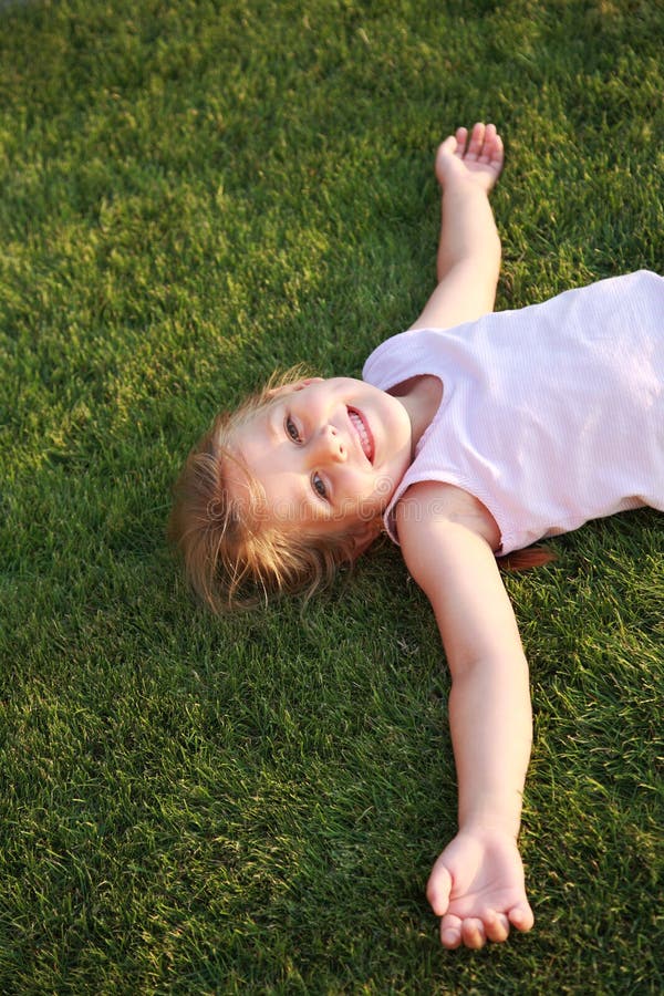 Fille heureuse détendant sur une herbe photo stock Fille heureuse détendant sur une herbe photo stock