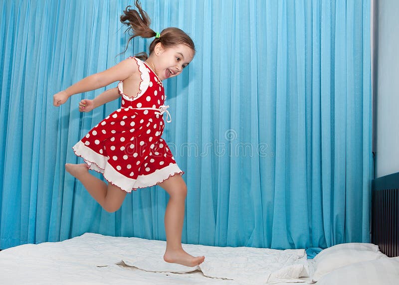 Fille heureuse sautant sur le lit photos libres de droits Fille heureuse sautant sur le lit photos libres de droits