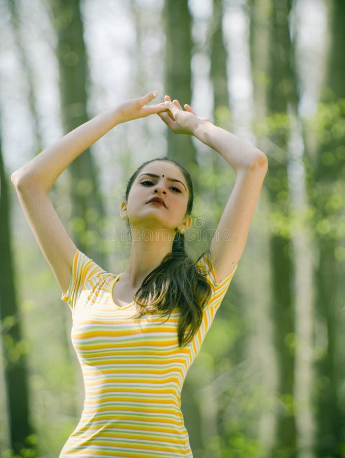 Indian girl meditating in the forest, arms lifted . Indian girl meditating in the forest, arms lifted .