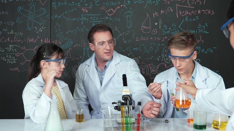 Fille inspecter le liquide coloré pendant que l'étudiant diversifié faire l'expérience. Édification banque de vidéos