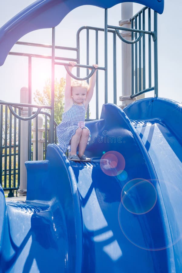 Fille jouant sur la glissière sur le terrain de jeu en été photo libre de droits Fille jouant sur la glissière sur le terrain de jeu en été photo libre de droits