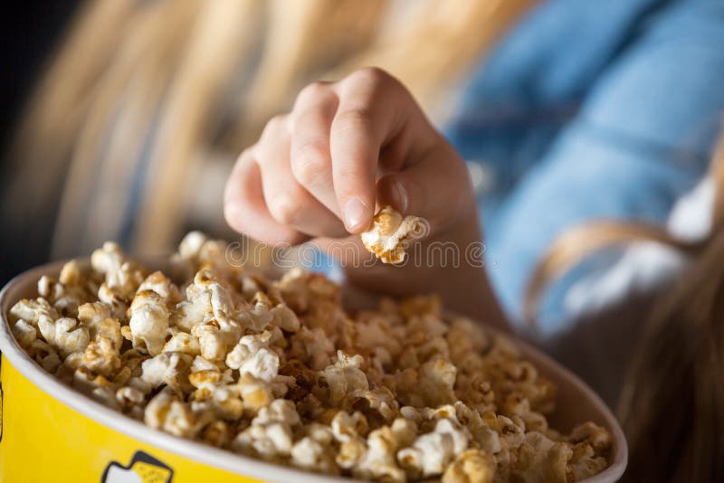 Fille mangeant du maïs éclaté dans le théâtre de cinéma images libres de droits Fille mangeant du maïs éclaté dans le théâtre de cinéma images libres de droits