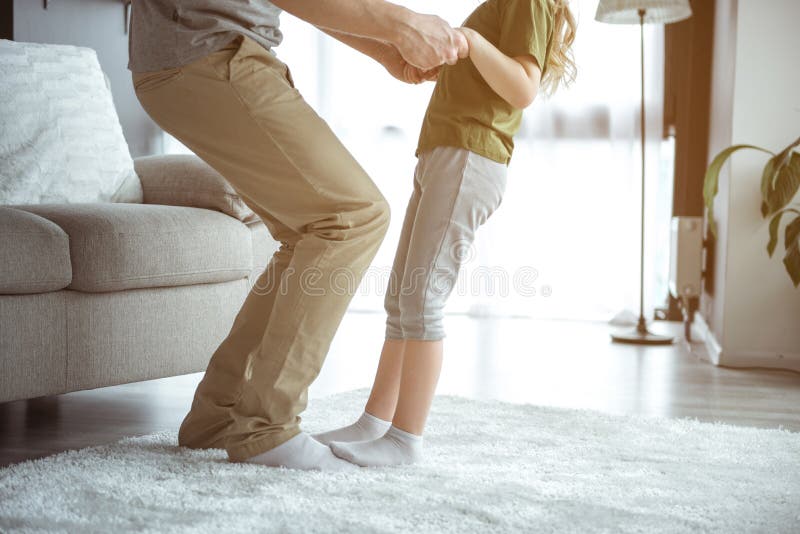 Fille mignonne appréciant la danse avec le papa dans la chambre image stock Fille mignonne appréciant la danse avec le papa dans la chambre image stock