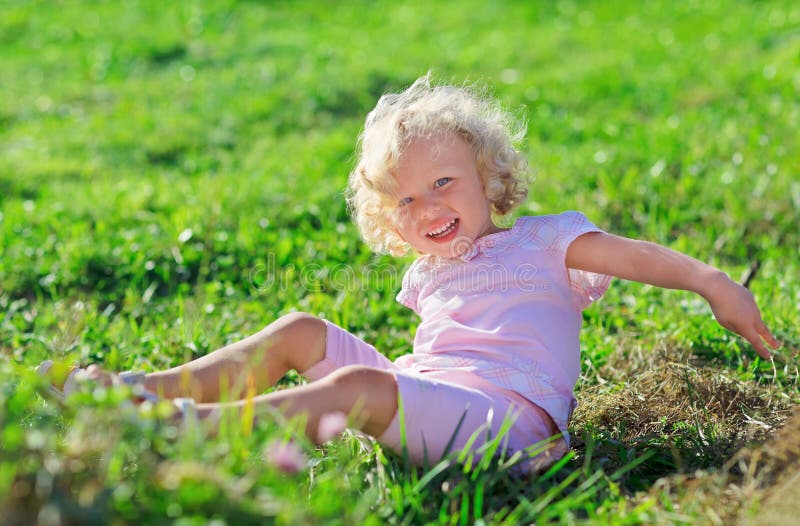 Fille mignonne avec le cheveu blond jouant sur la pelouse verte image libre de droits Fille mignonne avec le cheveu blond jouant sur la pelouse verte image libre de droits