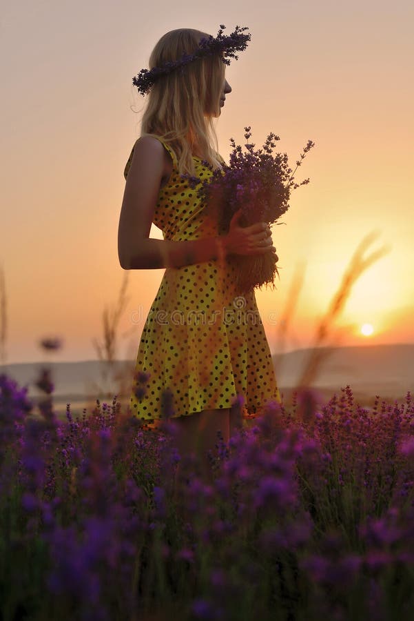 Fille mignonne avec une guirlande florale sur sa tête dans un domaine a de lavande photo libre de droits Fille mignonne avec une guirlande florale sur sa tête dans un domaine a de lavande photo libre de droits