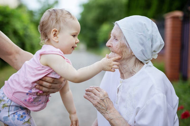 Fille mignonne d'enfant en bas âge jouant avec son arrière grand-mère et touchant son visage photographie stock libre de droits Fille mignonne d'enfant en bas âge jouant avec son arrière grand-mère et touchant son visage photographie stock libre de droits