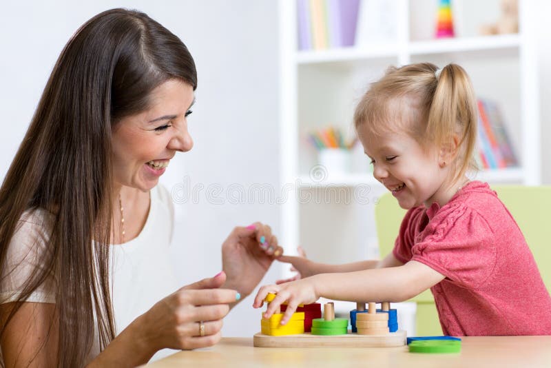 Fille mignonne de femme et d'enfant jouant les jouets éducatifs à la maison photo stock Fille mignonne de femme et d'enfant jouant les jouets éducatifs à la maison photo stock