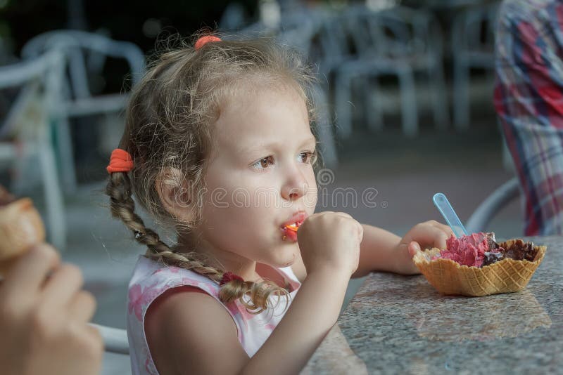 Fille mignonne mangeant son cône italien de gaufrette de crème glacée photos stock