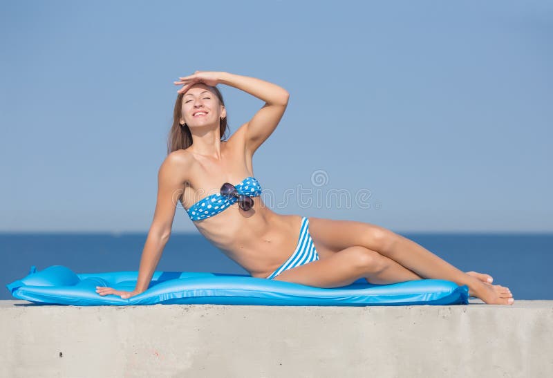 Fille mince dans les vêtements de bain reposant sur la piscine gonflable bleue photos stock Fille mince dans les vêtements de bain reposant sur la piscine gonflable bleue photos stock