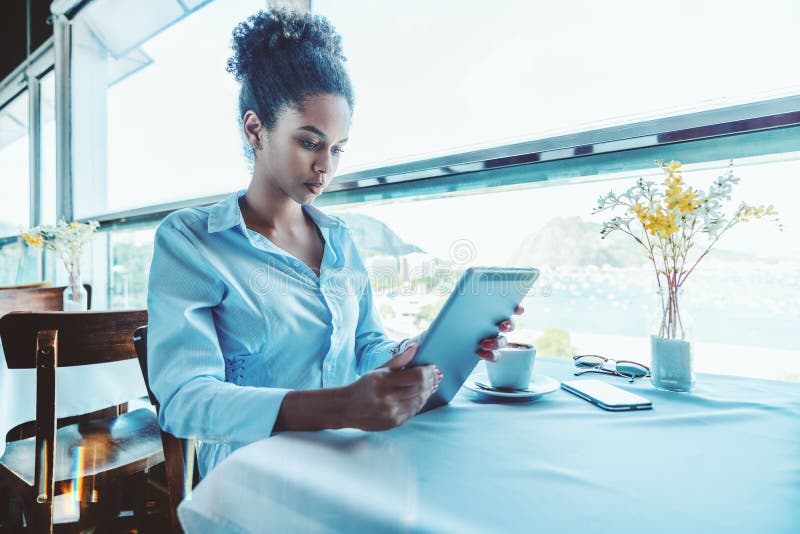 Fille noire réfléchie d'indépendant dans le restaurant avec le tabl numérique photos libres de droits Fille noire réfléchie d'indépendant dans le restaurant avec le tabl numérique photos libres de droits