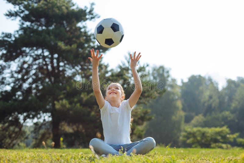 Une fille joyeuse lance une balle en l'air photographie stock