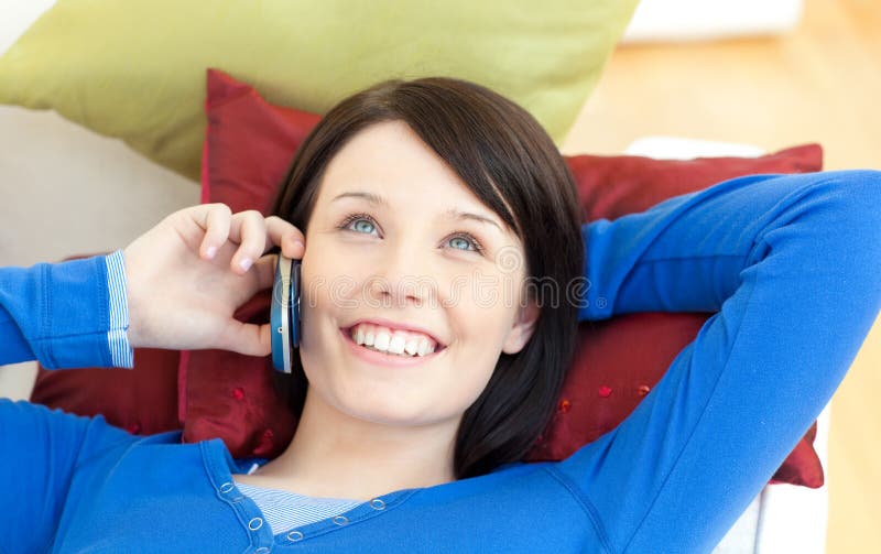 Fille parlant au téléphone se trouvant sur un sofa photos stock Fille parlant au téléphone se trouvant sur un sofa photos stock
