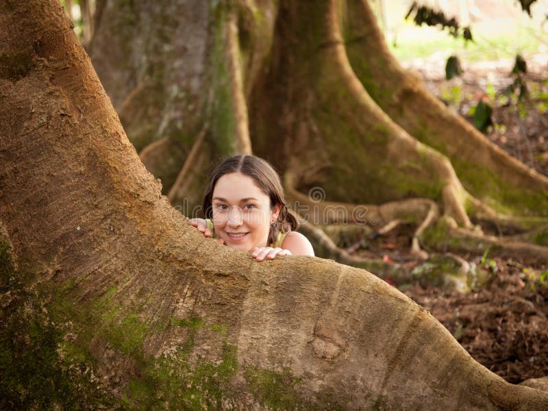 Girl looking from behind roots of the Moreton Bay fig tree. Girl looking from behind roots of the Moreton Bay fig tree