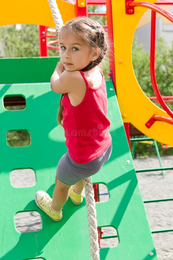 Fille préscolaire jouant sur le terrain de jeu, escaladant le mur sur une corde images libres de droits Fille préscolaire jouant sur le terrain de jeu, escaladant le mur sur une corde images libres de droits